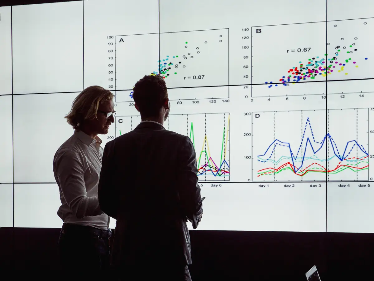 Zwei Experten analysieren Forecasting-Daten vor digitalen Zeitreihendiagrammen zur Prognose von Geschäftskennzahlen.
